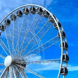 Large Ferris wheel against a bright blue sky at Scheveningen Pier, The Hague, with no visible people.