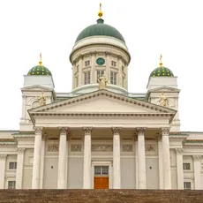 Helsinki Cathedral with its grand neoclassical facade and green domes under a bright white sky. The steps leading up are mostly empty, with two people near the bottom.