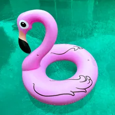 A pink flamingo pool float in bright turquoise water.