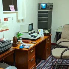 Vintage 1970s office setup with a retro computer, typewriter, old television, and office chairs.