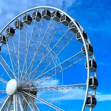 Large Ferris wheel against a bright blue sky at Scheveningen Pier, The Hague, with no visible people.