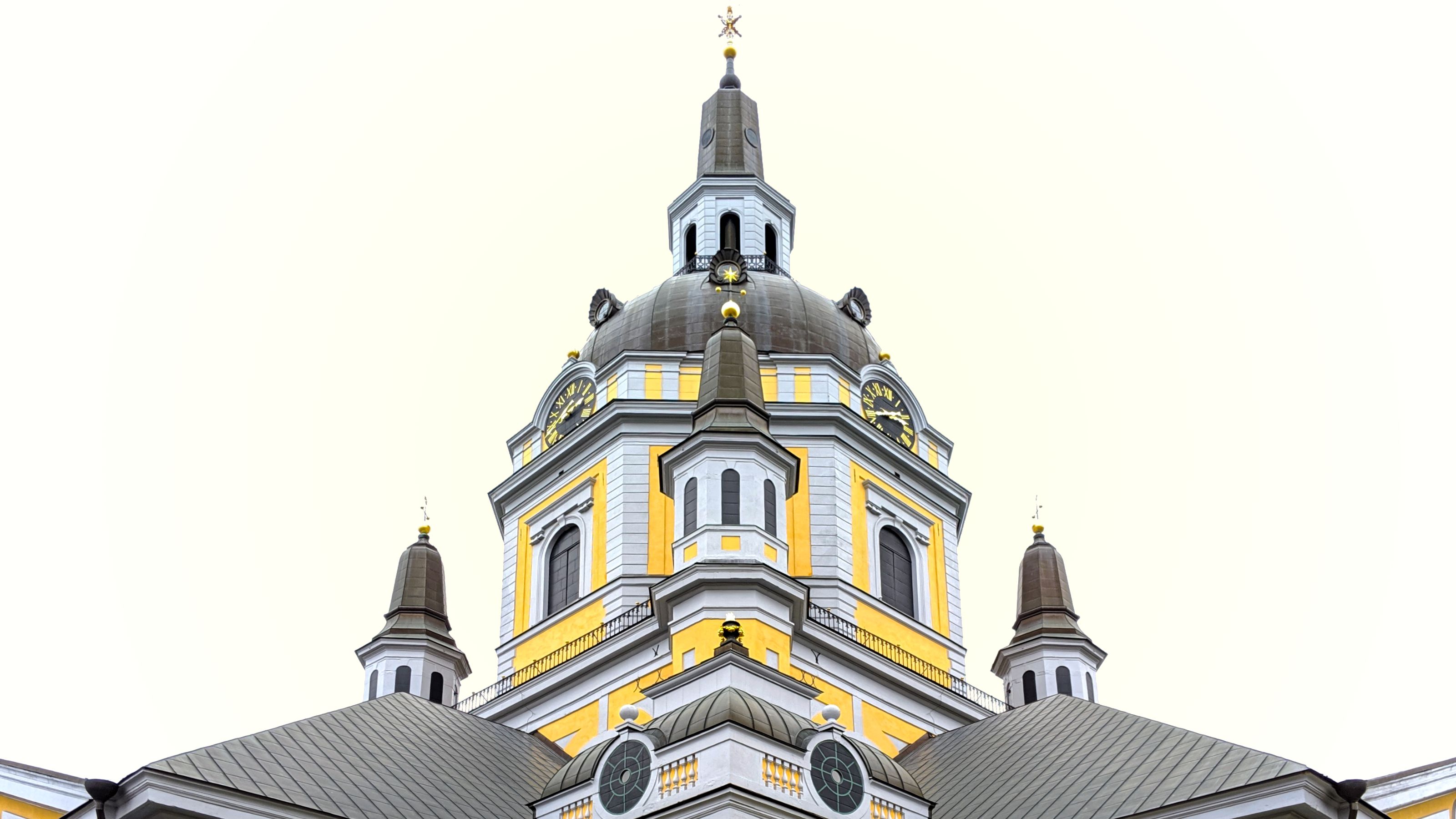 Symmetrical view of Katarina Church’s facade with a prominent dome. The structure features yellow accents, white walls, and dark roofs, set against a bright sky.